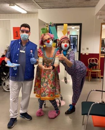 Eva Riepe som clownen Gajans och kollegan Ylva Magnusson som clownen Margott står med en medarbetare på vaccinationsmottagningen i Karolinska, Huddinge.