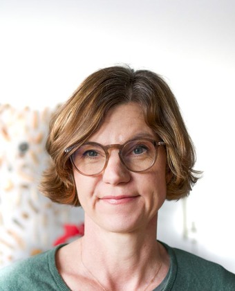 Pernilla Grillner har mellanblond page och runda bruna glasögon.