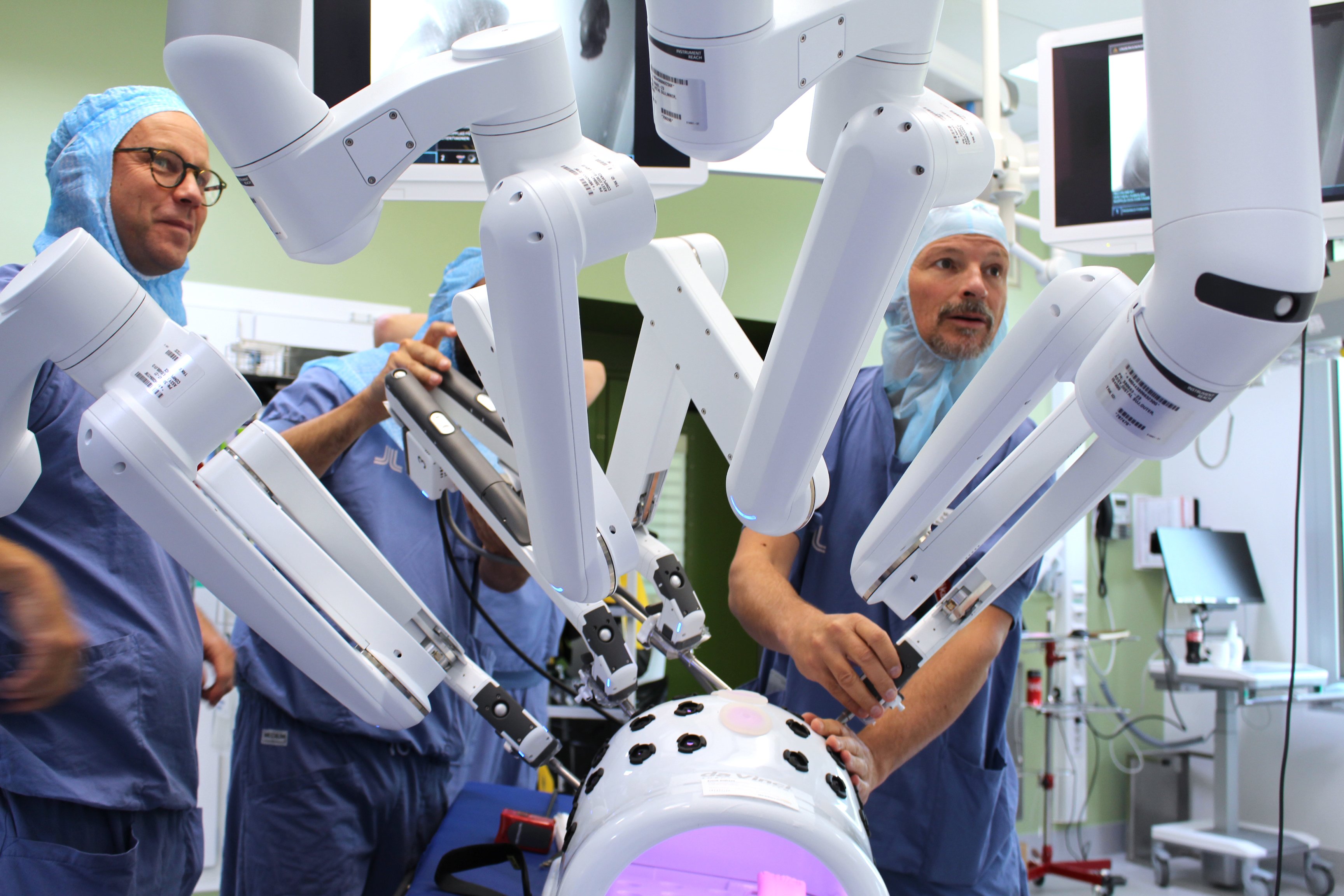 Två vårdklädda personer står vid medicins utrustning, en robot för operation.