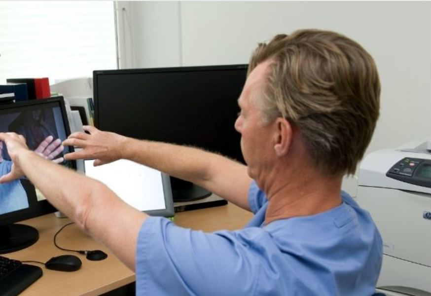 En person som håller upp händerna framför en datorskärm