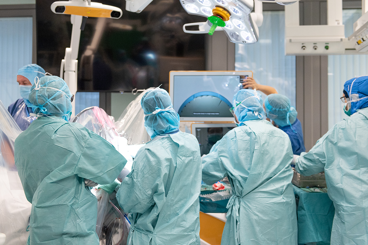 Ett operationsteam på sex neurokirurger står med ryggarna mot kameran framför ett operationsbord
