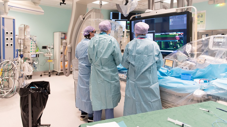 tre läkare tittar på en monitor för kranskärlsundersökning