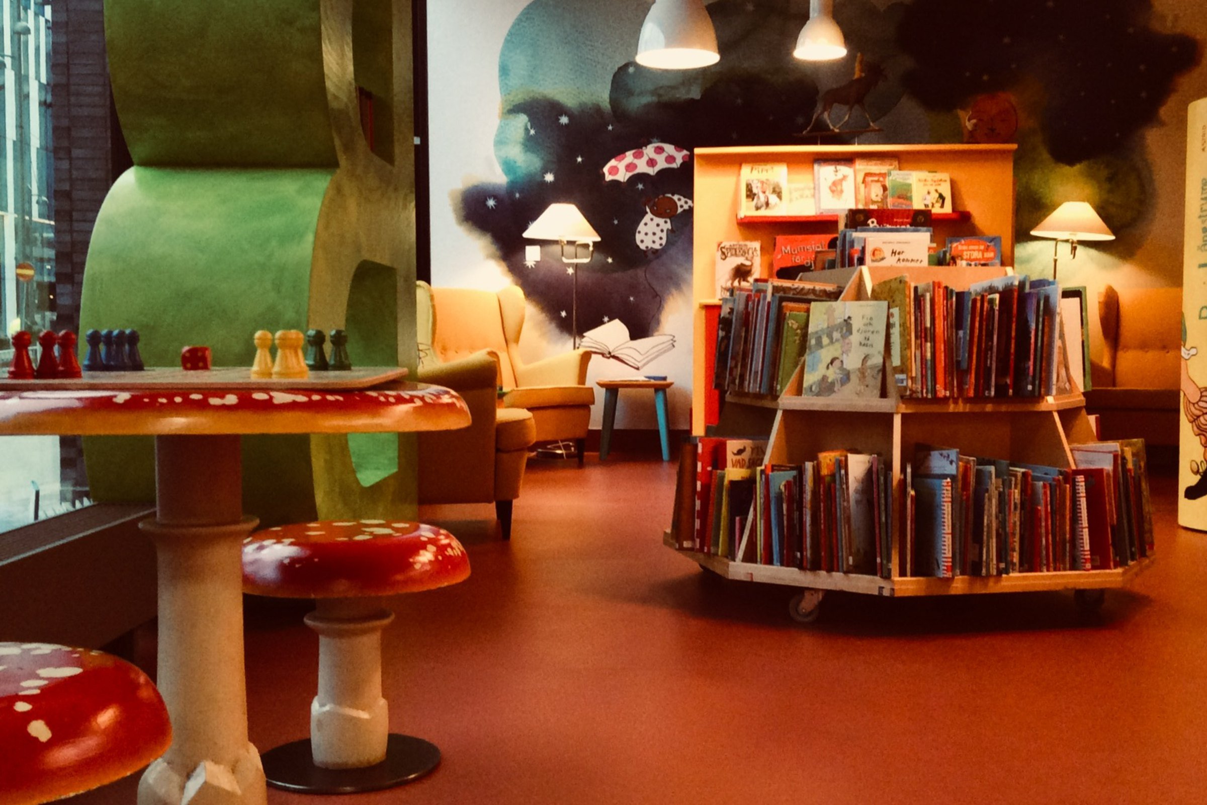 Rum med mysig och färgglad dekorering och böcker uppställda i runda hyllor.