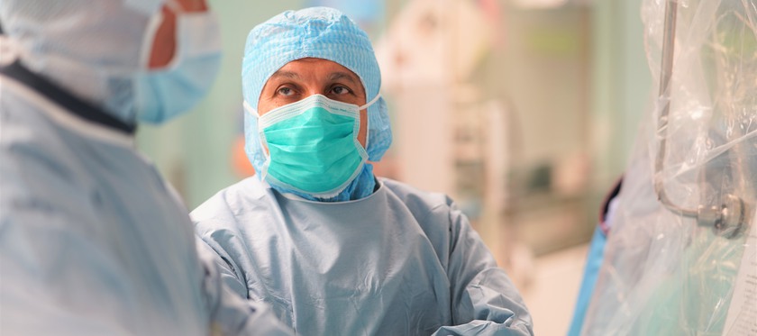 Manlig läkare står operationsklädd med armarna i kors